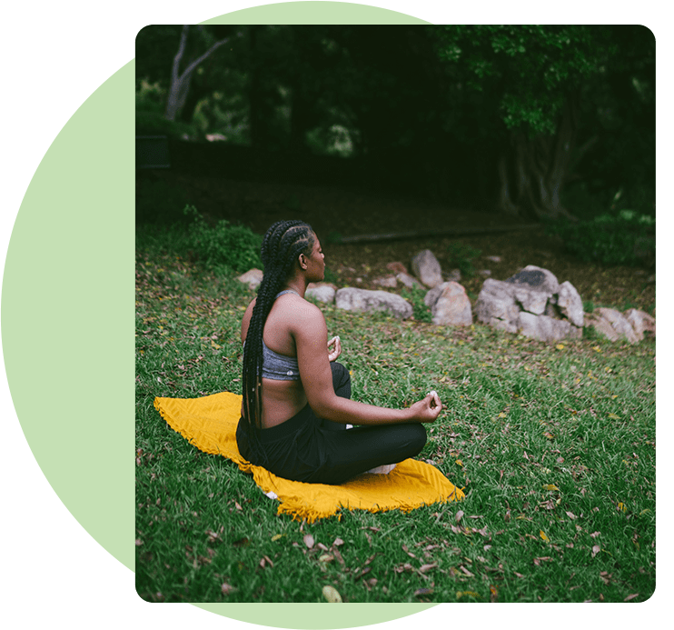 A woman sitting on the ground in a park.